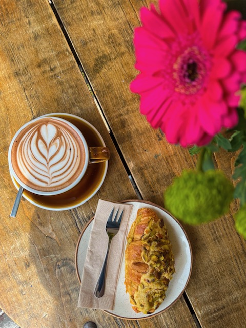 Latte art and a pistachio croissant in the sunshine