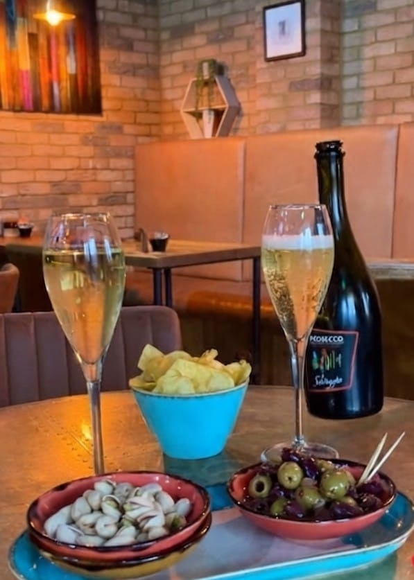 Prosecco, crisps, olives and pistachios on a table at Coffee Squared