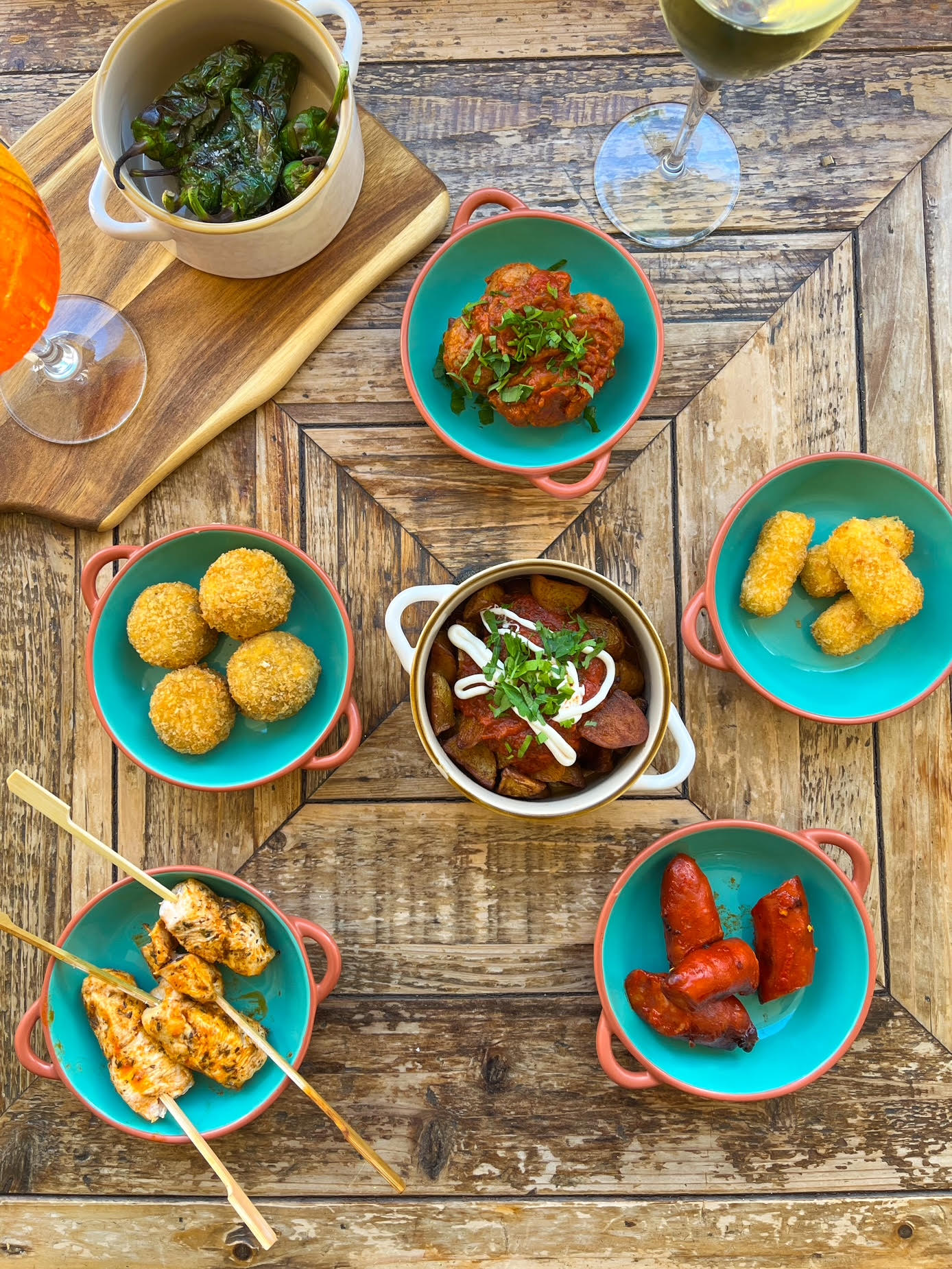 A spread of tapas — patatas bravas, croquettes, chorizo, padrón peppers and chicken skewers